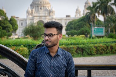 Victoria Anıtı 'nın önünde mavi gömlek giymiş genç ve yakışıklı bir Hintli Bengalli' nin portresi. Hint yaşam tarzı ve moda