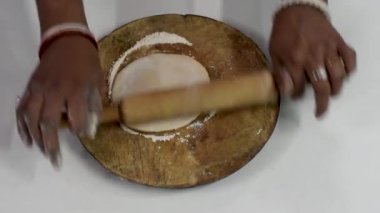 Mutfaktaki tahta belan chapati tahtasında roti hazırlayan bir kadının hızlı hareket eden elleri..