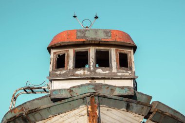 Turkuaz bir gökyüzü altında eski bir teknenin ön