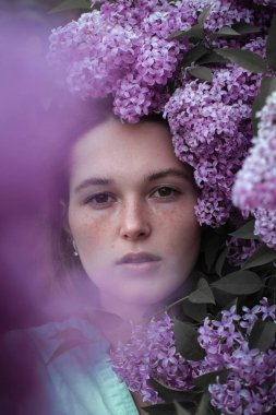 çiçeklerle çevrili güzel genç kadının moda fotoğrafı.