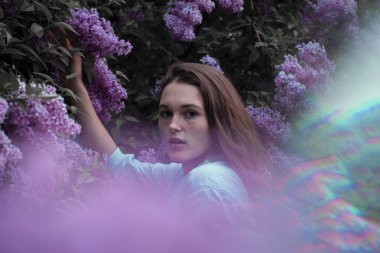 çiçeklerle çevrili güzel genç kadının moda fotoğrafı.