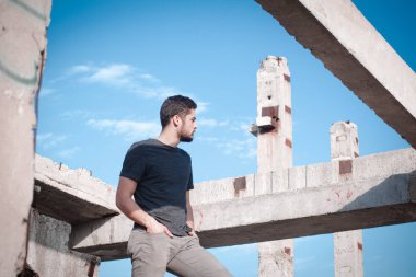 Sakallı, yakışıklı yüzlü, atletik yapılı genç bir adam. Fotoğraflar profesyoneldir.