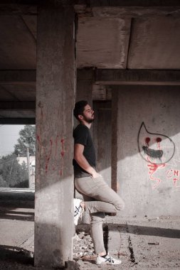 Sakallı, yakışıklı yüzlü, atletik yapılı genç bir adam. Fotoğraflar profesyoneldir.