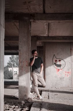 Sakallı, yakışıklı yüzlü, atletik yapılı genç bir adam. Fotoğraflar profesyoneldir.