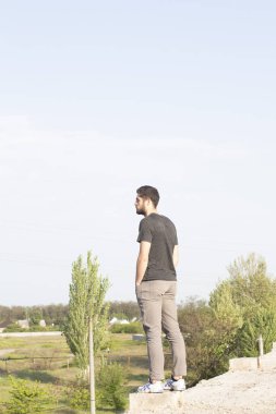 Sakallı, yakışıklı yüzlü, atletik yapılı genç bir adam. Fotoğraflar profesyoneldir.