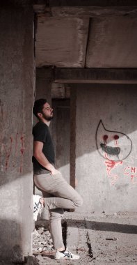 Sakallı, yakışıklı yüzlü, atletik yapılı genç bir adam. Fotoğraflar profesyoneldir.