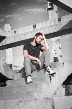 Sakallı, yakışıklı yüzlü, atletik yapılı genç bir adam. Fotoğraflar profesyoneldir.