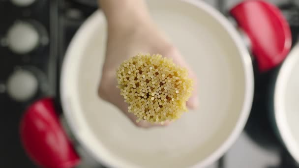 沸騰した水で鍋にマカロニを入れる女性の手のスローモーション — ストック動画