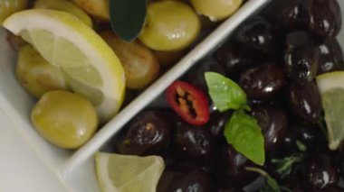 Beyaz plaka limon dilimleri ile yeşil ve siyah zeytin üst görünümü 