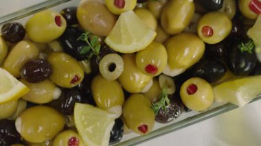 Beyaz plaka yağ ile dökme limon dilimleri ile yeşil ve siyah zeytin üst görünümü