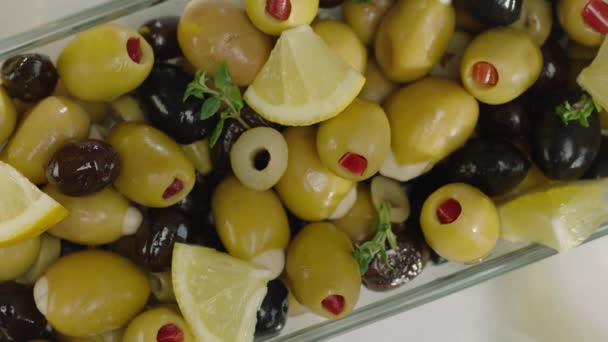 绿色和黑色橄榄与柠檬片在白色盘子浇注油的顶视图 — 图库视频影像
