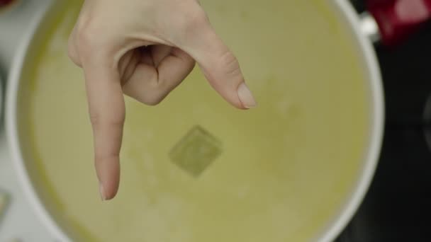 スープにスパイシーなキューブを投げる女性の手のスローモーション — ストック動画