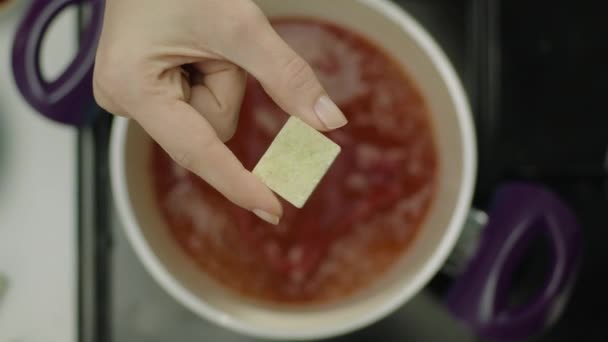 スープにスパイシーなキューブを投げる女性の手のスローモーション — ストック動画