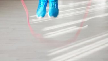 Mavi spor ayakkabılı atletizm adamının yakın çekimi ip atlamaya, atlamaya ve atlamaya başlıyor.