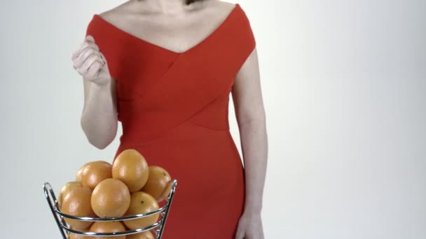 オレンジだ空気中にオレンジを投げ 保持する女性 バスケットと赤いドレスのオレンジ 白い背景 — ストック動画