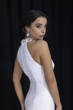 Zarif, beyaz bir gelinlik içinde, sırtı mücevherlerle kaplı, zarif ve gelinlik tarzı olan bir gelin..