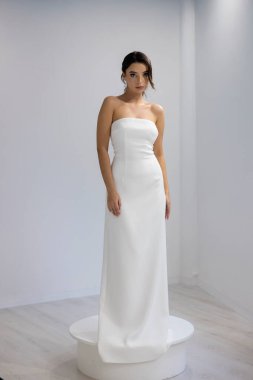 Askısız beyaz gelinlik içinde güzel bir gelin zarif ve şık bir iç mekan portresi.