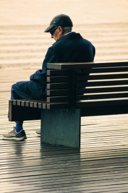 yaşlı adam bir bankta tek başına oturan