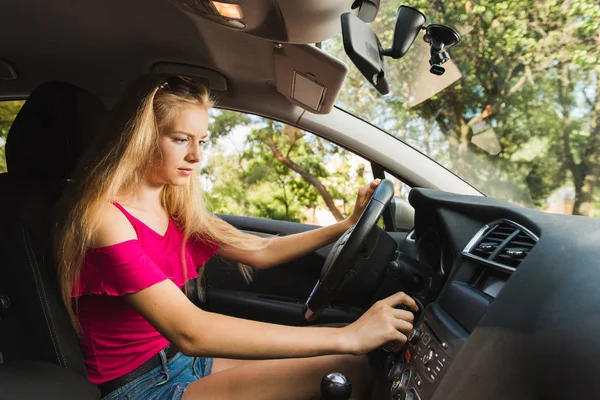 Confused young blond girl insert car key — Stock Photo, Image