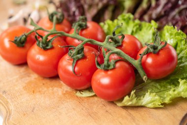 Kiraz domates ahşap masa üzerinde Şubesi Close-up. Marul yaprakları.
