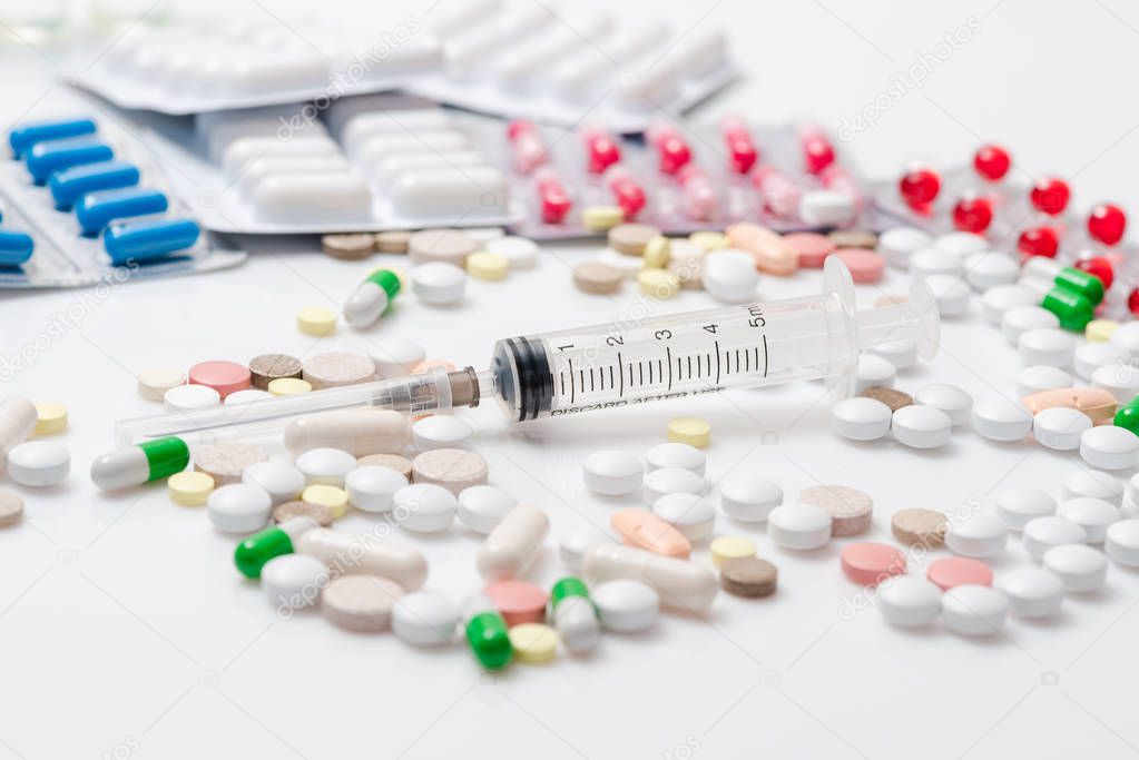 Many colorful medicines. Pills capsules and syringe, blister packs on white background. Top view.