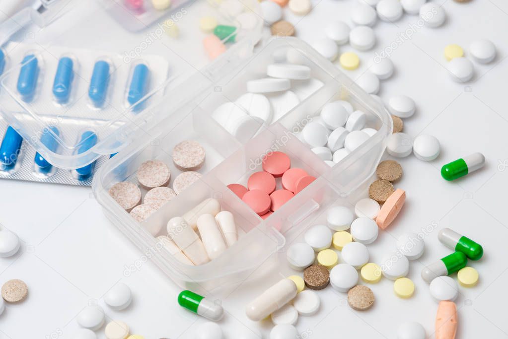 Close-up of pill case with various colorful medications on white background.