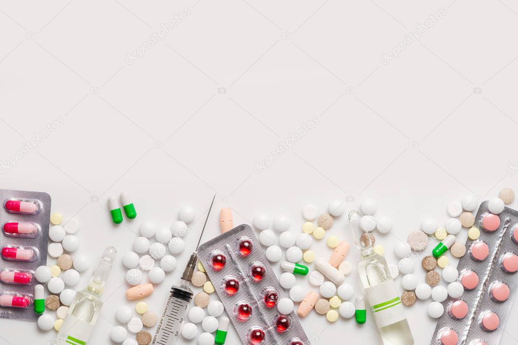 Colorful medication and pills, capsules in blister packs, a syringe, ampoule on white background. Top view with copy space, flat lay.
