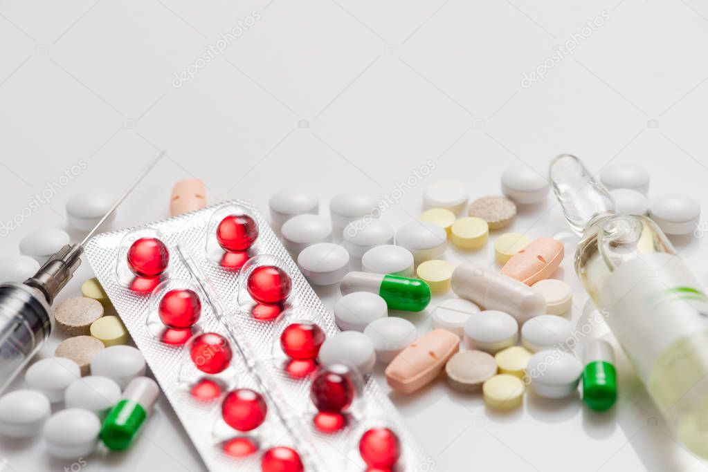 Many colorful medicines. Pills capsules and syringe, blister packs on white background. Top view with copy space, flat lay.