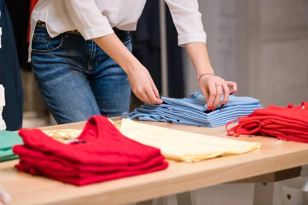 Mujer doblar ropa azul en la tienda de ropa . — Foto de Stock