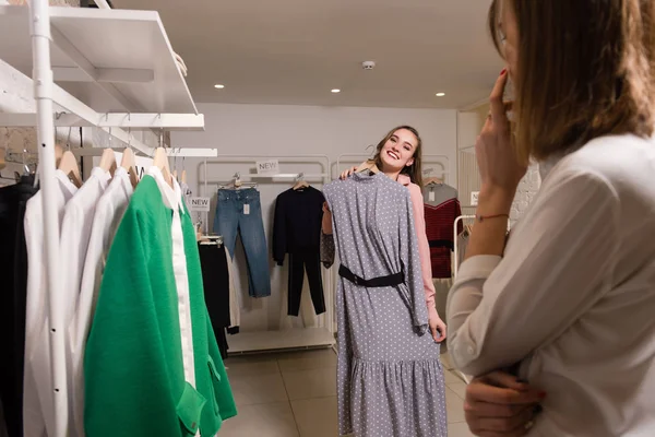 Sonriente hembra probar en vestido largo en la tienda de ropa . — Foto de Stock