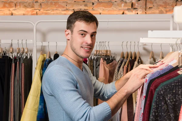 Joven hombre sonriente comprando en ropa en la tienda . — Foto de Stock
