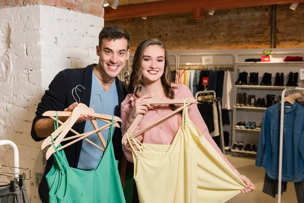 Feliz pareja sonriente con ropa en la tienda de ropa — Foto de Stock