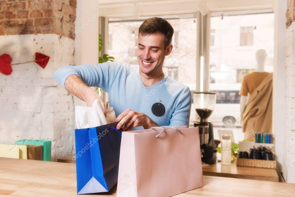 Man packs purchases in paper shopping bag