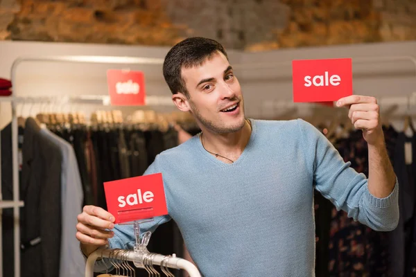 Vendedor tiene dos signos rojos con palabra venta — Foto de Stock