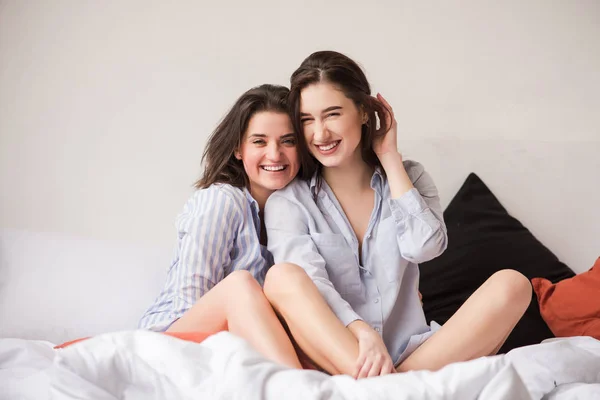 Retrato de duas mulheres atraentes abraçando na cama . — Fotografia de Stock