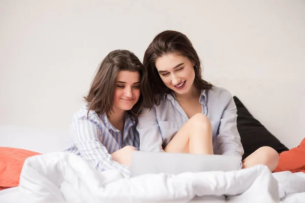 Dos mujeres atractivas con portátil en la cama — Foto de Stock