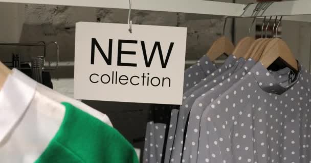 Novo sinal de coleção na loja de roupas com cabides — Vídeo de Stock