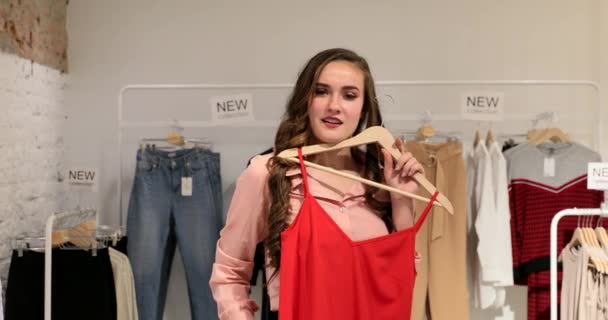 Молода жінка, що володіє і дрібничка на одязі в магазині — стокове відео