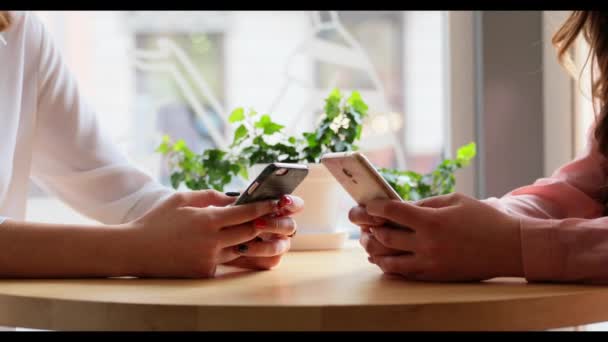 Δύο γυναίκες που κάθεται με τα τηλέφωνα και πληκτρολογώντας ένα μήνυμα. — Αρχείο Βίντεο