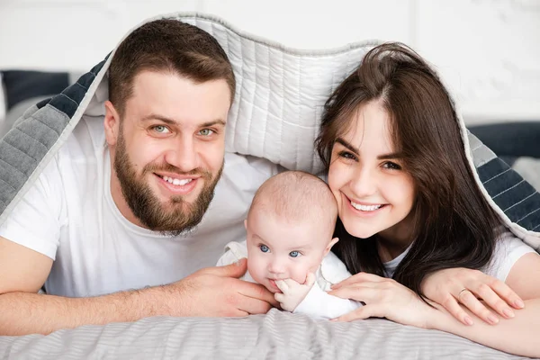 Tineri familie zâmbitoare cu fiica sub pătură — Fotografie, imagine de stoc