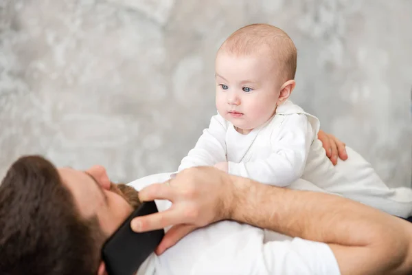 Padre habla por teléfono y juega con el bebé — Foto de Stock