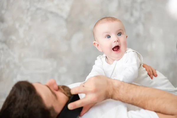 Padre habla por teléfono y sostiene al bebé — Foto de Stock