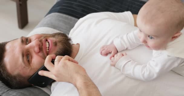 Pai fala por telefone e brinca com bebê . — Vídeo de Stock