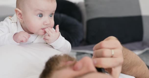 Fadern pratar per telefon och leker med babyn. — Stockvideo
