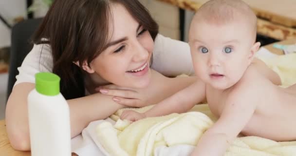 Lachende moeder en baby meisje met fles huidverzorging. — Stockvideo