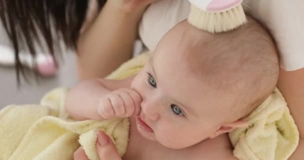 Giovane donna sorridente pettinando i capelli bambino, primo piano . — Video Stock