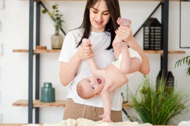 Young mother hold upside down smiling baby.