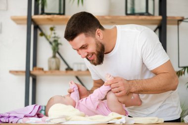 Young man play with his laying baby girl.