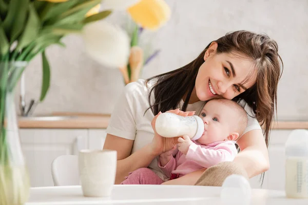 Woman feeding newborn with formula in a bottle.