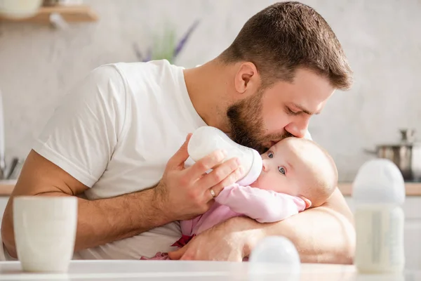 Padre joven besar a su bebé durante el consumo de leche — Foto de Stock